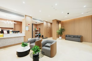 A modern reception area with a counter, seating, and a potted plant.