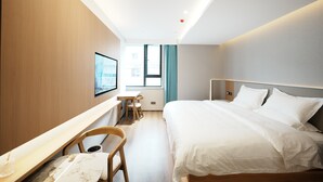 Una habitación de hotel con cama, escritorio, silla y ventana.
