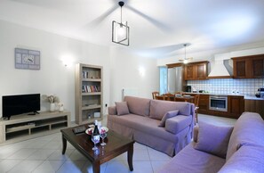 A living room with a sofa, a coffee table, a TV, and a bookshelf. - Serene Apartment Lefkada (Lefkada)