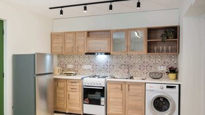Une cuisine compacte équipée d’un réfrigérateur, d’une cuisinière, d’un four et d’un lave-linge.
