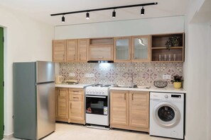 A compact kitchen with a refrigerator, stove, oven, and washing machine. - Boukamvillia Apartment, just 500m from Nidri Beach (Nydri)