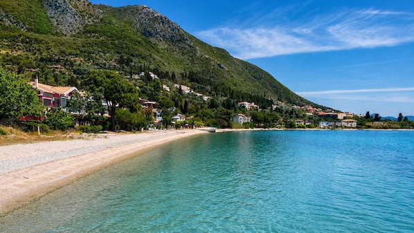 A coastal town with a beach, houses, and a mountain in the background. - Boukamvillia Apartment, just 500m from Nidri Beach (Nydri)