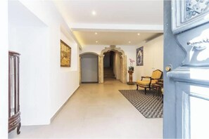 Um corredor com escadas, uma porta, uma cadeira e um tapete.