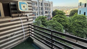 Ein Balkon mit Wasserspender, Blick auf Gebäude und Boden mit grünem Kunstrasen.
