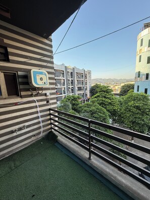 Un balcón con dispensador de agua, vistas a edificios y piso cubierto de césped artificial.