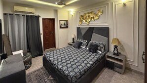 Ein Schlafzimmer mit Bett, Nachttischen, Deckenventilator, Wandklimaanlage und einer Wanddekoration.