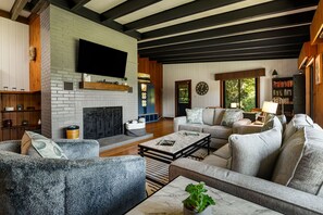 Ein modernes Wohnzimmer mit Kamin, Sofas, einem Couchtisch und einem Fernseher.
