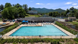 Ein rechteckiger Swimmingpool mit einer Liegefläche, Liegestühlen und einem überdachten Pavillon.