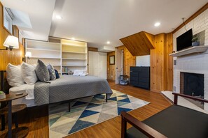 Ein modernes Schlafzimmer mit Bett, Nachttischen, Fernseher, Kamin und eingebauten Regalen.