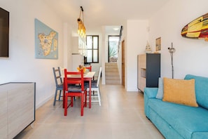 A modern living room with a teal sofa, a dining table with chairs, a staircase, and a kitchen area. - 2BR Las Americas, Pool, Terrace, AC, 1Gb Wifi (Arona)