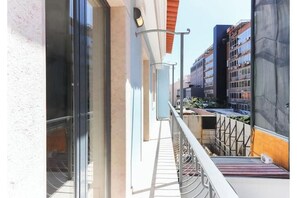 A balcony with a metal railing, a glass door, and a building with multiple floors in the background. - Av. Liberdade: A luxurious and peaceful duplex with a balcony and parking (Lisboa)