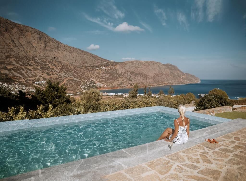 Una piscina con vistas despejadas al mar y montañas al fondo.