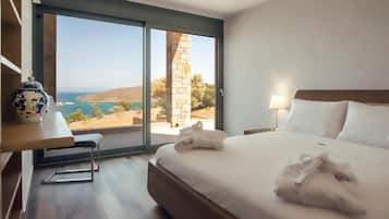 Habitación de hotel con una cama grande, un escritorio con un florero y vista al mar.