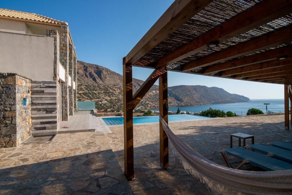 Un espacio al aire libre cubierto con piscina, escalones de piedra y vistas al mar y las montañas.
