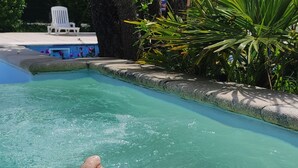 Ein Swimmingpool, umgeben von Palmen und einem weißen Stuhl.