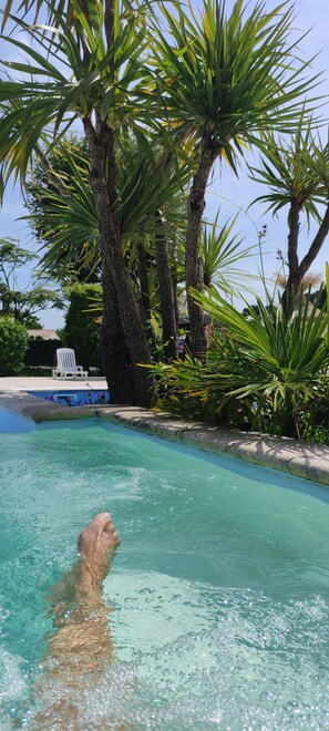 Ein Swimmingpool, umgeben von Palmen und einem weißen Stuhl.