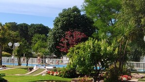 Ein gepflegter Garten mit Schwimmbad, Kiesweg und üppiger Vegetation.
