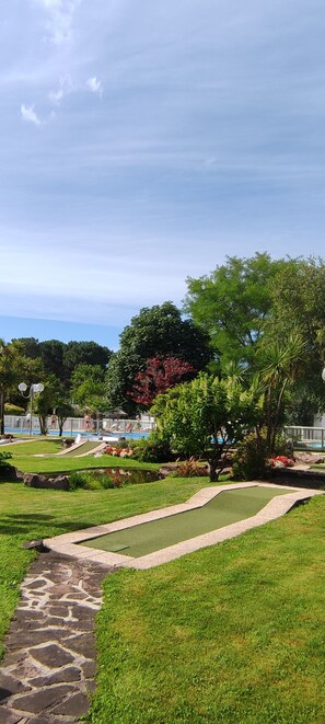 Ein gepflegter Garten mit Schwimmbad, Kiesweg und üppiger Vegetation.