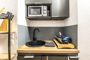 Eine kleine Küche mit Mikrowelle, Spüle und Holz Arbeitsplatte.