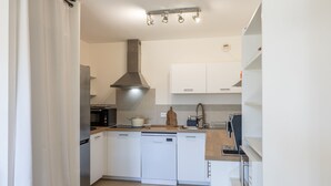 Een moderne keuken met witte kastjes, een roestvrijstalen afzuigkap en een vaatwasser.