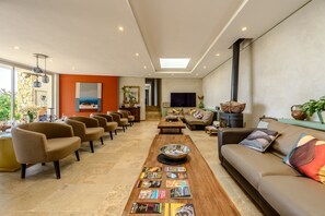 A spacious living area with a long wooden coffee table, multiple seating options, and a large TV. - Villa Labori - Piscine intérieure et extérieure (Gigondas)