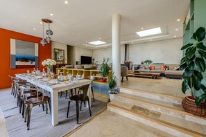 A spacious living area with a dining table, chairs, sofas, and a staircase leading to another level. - Villa Labori - Piscine intérieure et extérieure (Gigondas)