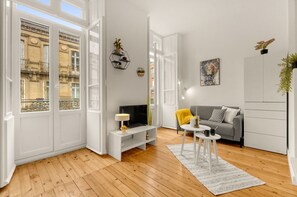 Moderni olohuone, jossa on televisio, sohva ja sohvapöytä. Huoneessa on puulattia ja valkoiset seinät.
