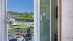 Ein Zimmer mit einer Schiebeglasdoor zum Balkon mit Blick auf Häuser und Grünflächen.