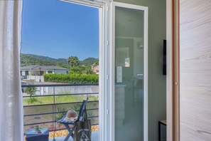 Ein Zimmer mit einer Schiebeglasdoor zum Balkon mit Blick auf Häuser und Grünflächen.