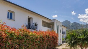 Ein modernes Gebäude mit Balkon, blauem Himmel und einem Berg im Hintergrund.