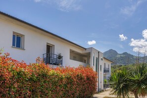 Ein modernes Gebäude mit Balkon, blauem Himmel und einem Berg im Hintergrund.