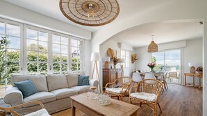 Uma sala ampla com sofá, cadeiras, mesa de centro de madeira e mesa de jantar.