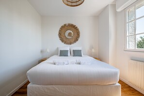 Ein ordentlich bezogenes Bett mit weißen Laken, zwei Kissen und einer Wanddekoration.