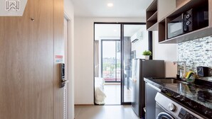 Et moderne køkken med indbygget ovn, mikroovn og opvaskemaskine. Der er en skydedør til en balkon.