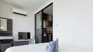 A hotel room with a bed, a desk, a television, and a kitchenette. - Modern Cozy Condo in Ratchada 36 Perfect for 10+ Nights (Krung Thep Maha Nakhon)