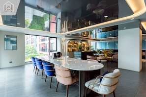 Un interior moderno con una mesa central tipo isla, asientos y vistas al exterior.