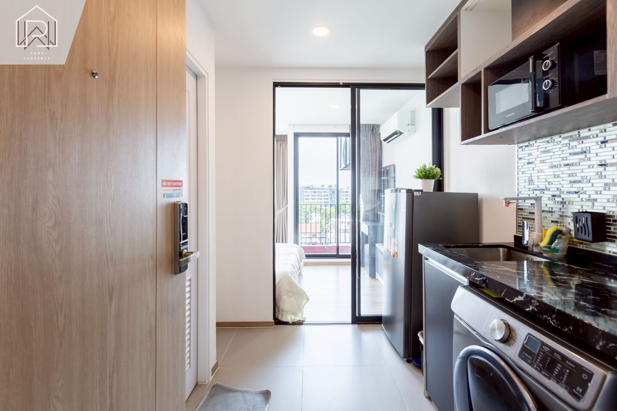 A modern kitchen with a built-in oven, microwave, and dishwasher. There is a sliding glass door leading to a balcony.
