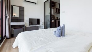 Een hotelkamer met een bed, een bureau, een televisie en een kitchenette.