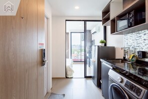Cocina moderna con horno empotrado, microondas y lavavajillas. Hay una puerta corrediza de vidrio que da a un balcón.