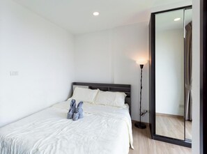 Un dormitorio con cama, lámpara de noche y espejo.