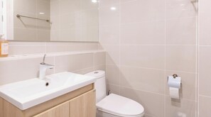 Un baño con lavamanos, inodoro y espejo blancos.
