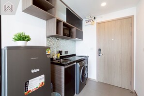 Eine kompakte Küche mit Kühlschrank, Waschmaschine und Mikrowelle.