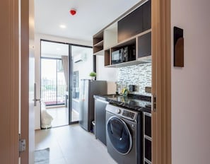 Een kleine keuken met een wasmachine, een magnetron en een klein aanrecht.