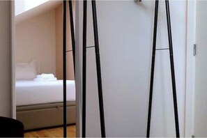 Ein Schlafzimmer mit einem Bett, einer weißen Wand und einer schwarzen Leiter, die an der Wand lehnt.