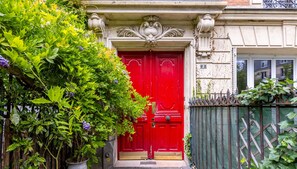 Una porta rossa con un arco decorativo, un cartello con il numero 2 e un cancello in metallo.