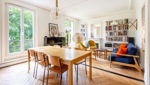 A spacious living area with a dining table, chairs, a sofa, a bookshelf, and a fireplace. - Montmartre Sacré Coeur - Superbe appart pour 2 (Paris)