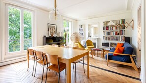 A spacious living area with a dining table, chairs, a sofa, a bookshelf, and a fireplace. - Montmartre Sacré Coeur - Superbe appart pour 2 (Paris)