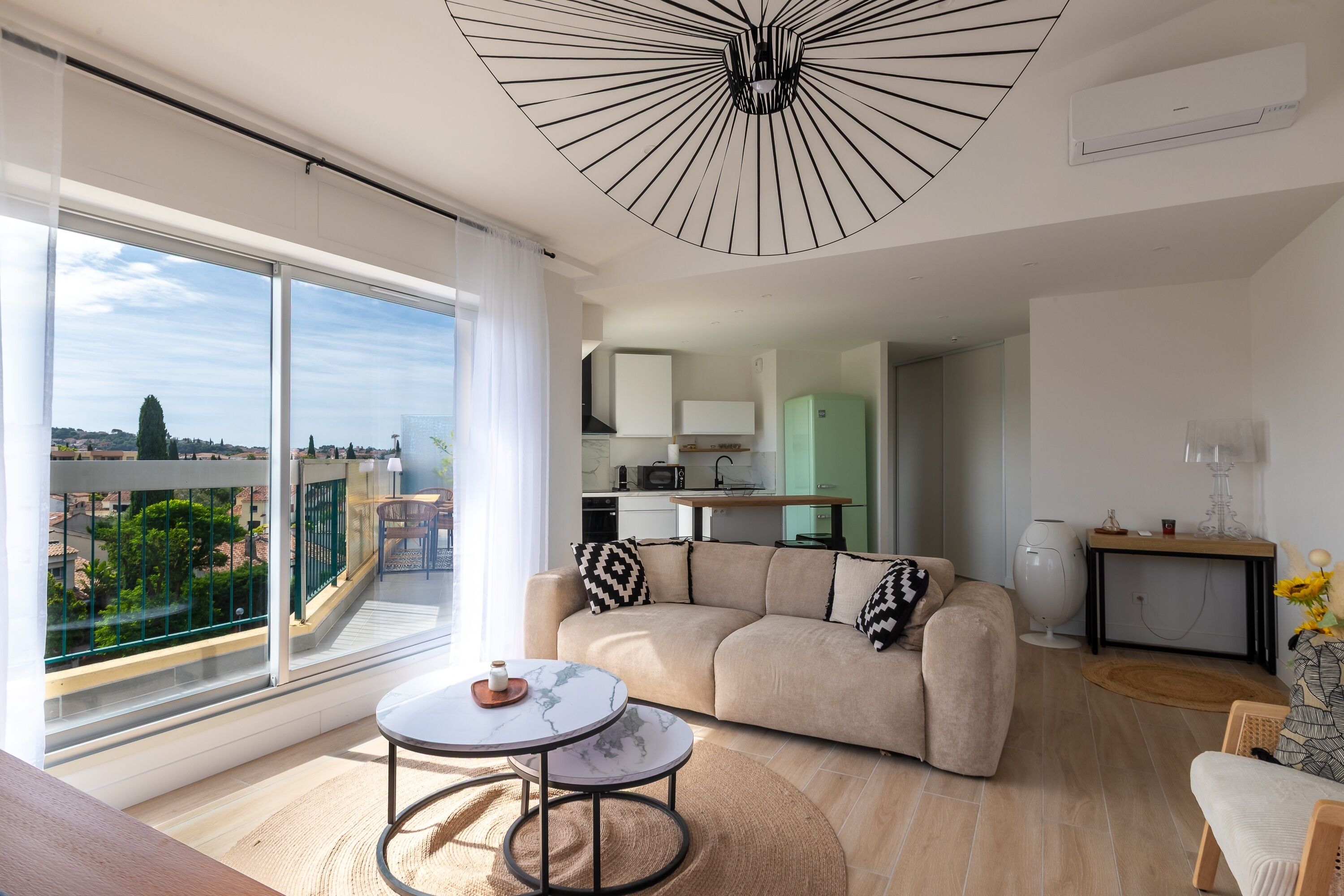 A modern living room with a sofa, a coffee table, and a view of the city through large windows.