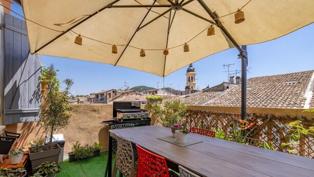 An outdoor patio with a table and chairs, a grill, potted plants, and a view of buildings in the background. - La Terrasse de Vidauban - Duplex climatisé (Vidauban)