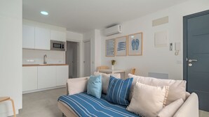 Ein modernes Wohnzimmer mit einer Couch, einem kleinen Tisch und einer Küchenzeile im Hintergrund.